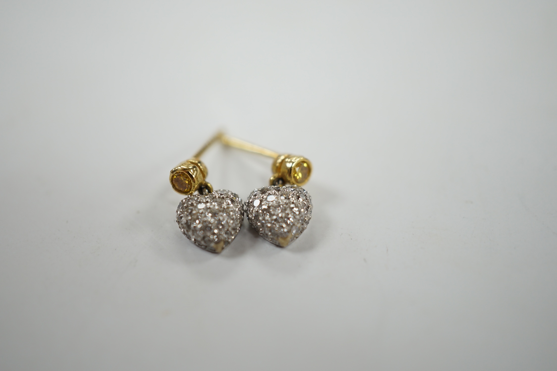 A modern pair of 750 and pave set diamond chip heart shaped ear studs, with single stone yellow diamond set bale, 9mm, gross weight 1.9 grams. Condition - good